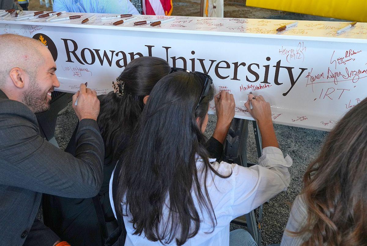 Attendees sign the final beam to be raised in the facility's framework